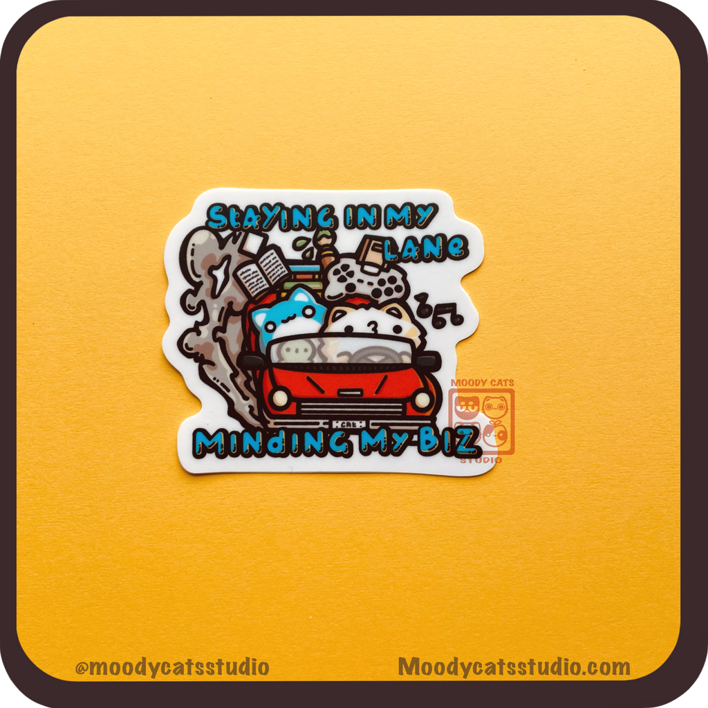 Sticker with a cat in a car with various hobbies and text 'Staying in my lane, minding my biz'